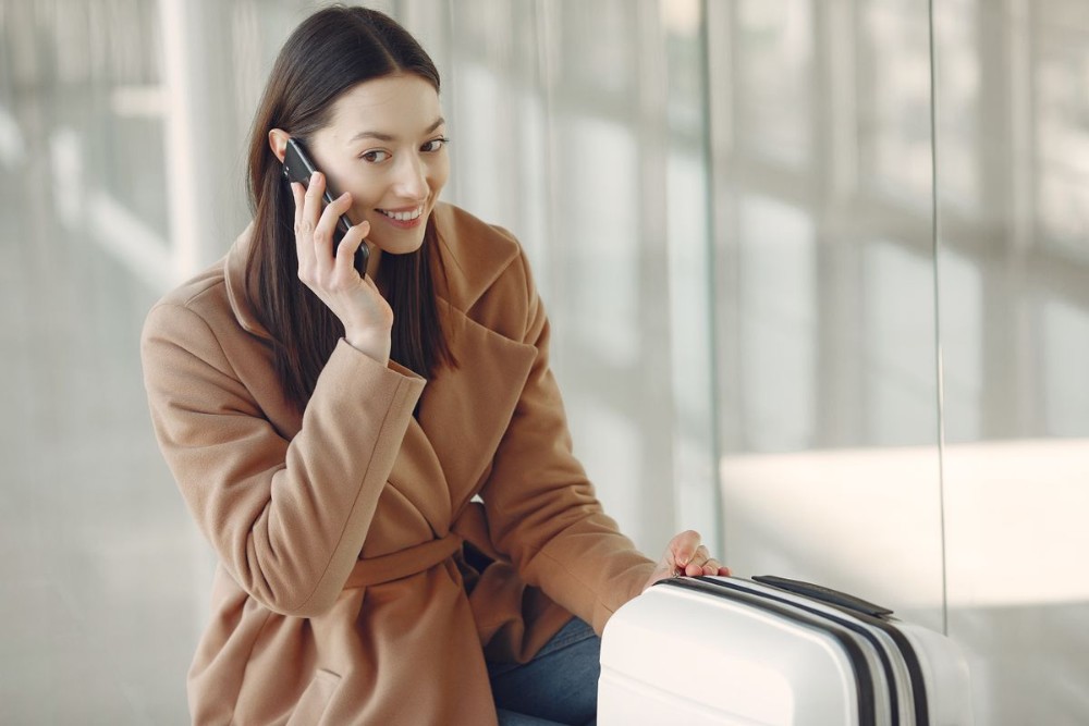 Viajera esperando su vuelo y llamando para resolver si necesita seguro de viaje o asistencia de viaje